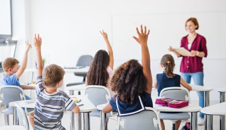 children raising hands in a classroom